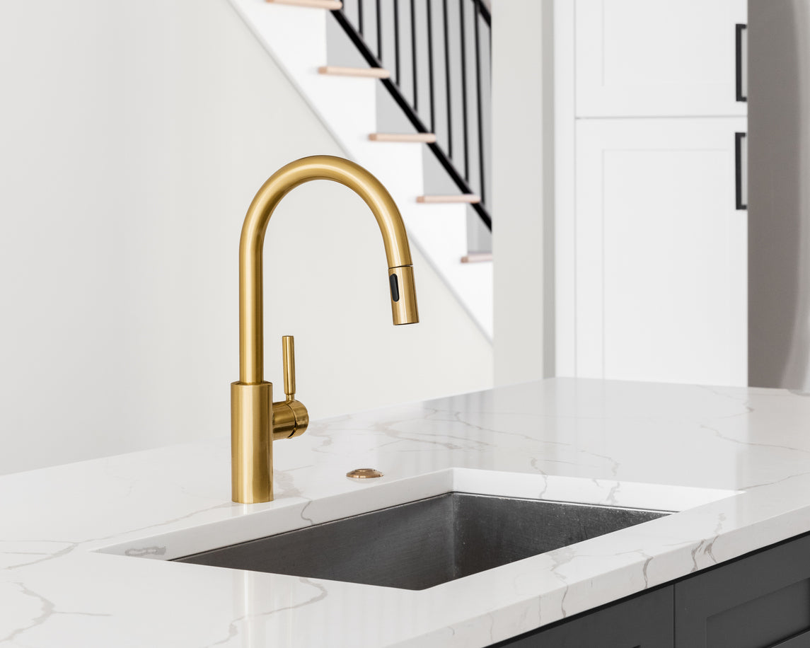 The Tap Collection website hero image. Gold swan neck style kitchen tap in a contemporary kitchen setting