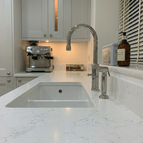 Charlbury kitchen handspray in chrome beside a curved kitchen tap on a marble worktop