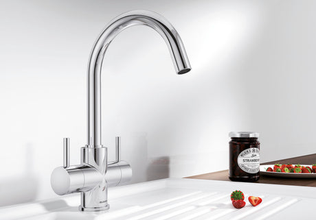BLANCO Camia Dual Lever C-Shaped Kitchen Mixer Tap in Chrome on a White Sink Drainer