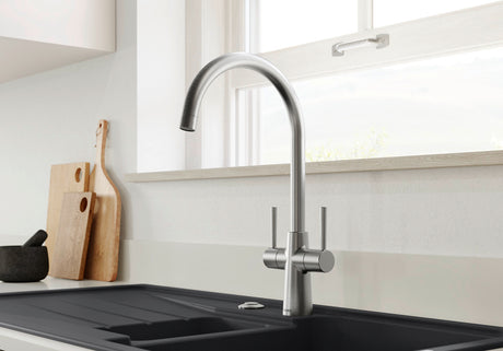 BLANCO Max II Dual Handle Kitchen Mixer Tap with 360° Swivel Spout in PVD Steel in Front of a Window